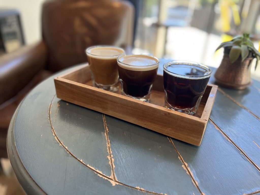 table holding a coffee flight tray with three coffees