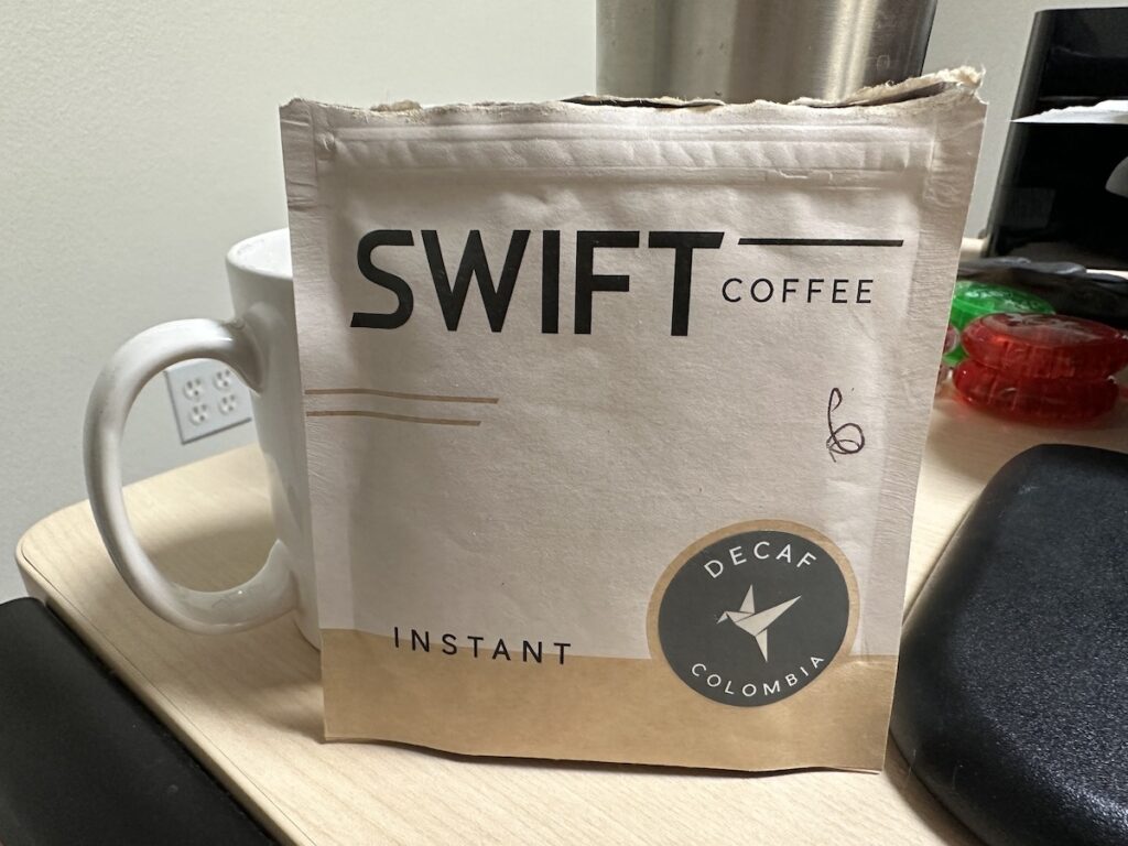 package of swift instant decaf coffee and coffee cup